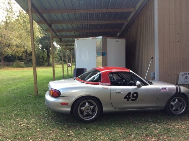 A silver sports car parked in the grass.
