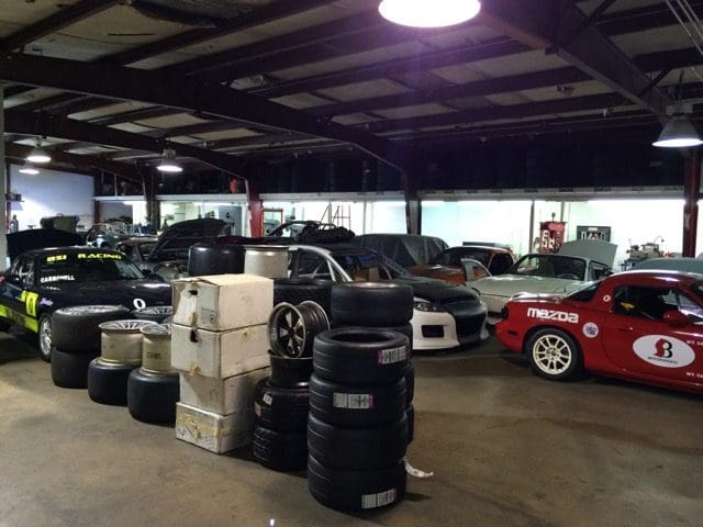 A car shop with many tires stacked on top of each other.