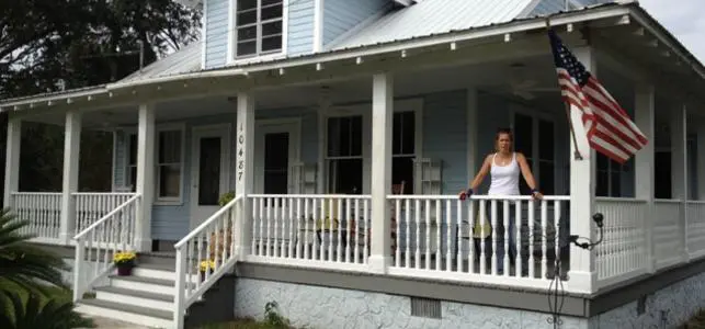 A woman standing on the porch of her home.