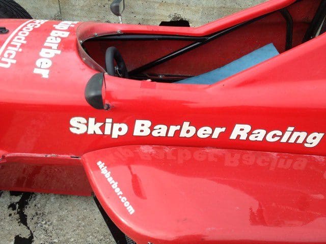 A red race car with the name " skip barber racing ".