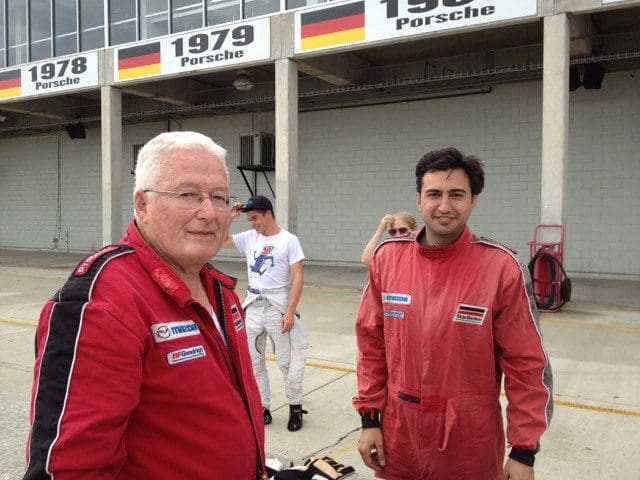 Two men in red racing suits standing next to each other.
