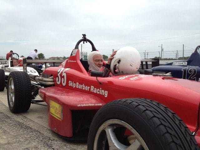 A man in a red race car driving on the track.