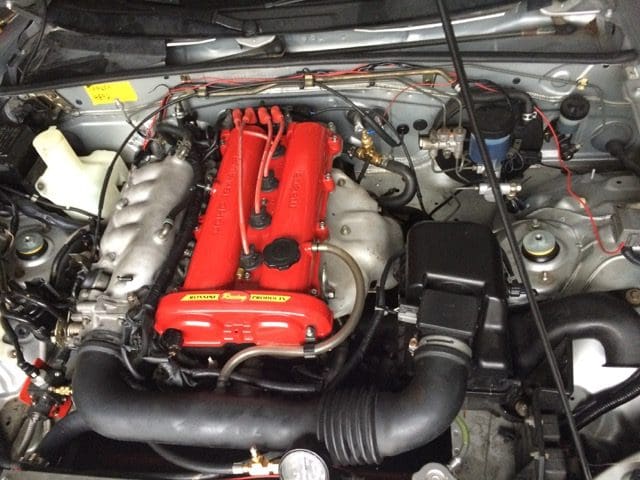 A car engine with the hood open and the engine bay exposed.
