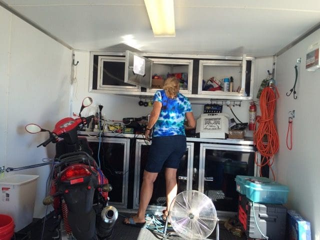 A woman standing in the garage with her bike.