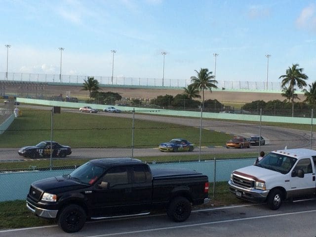 A group of trucks parked in the middle of an empty race track.