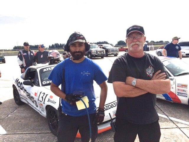 Two men standing next to a race car.