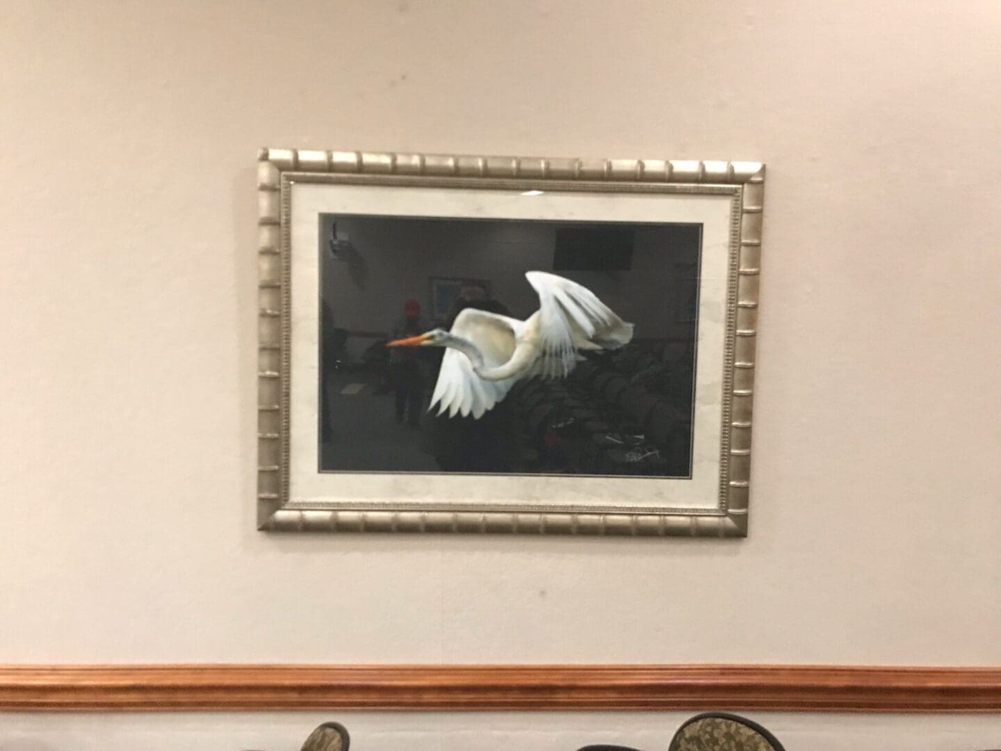 A framed painting of a white egret on the wall captures the beauty of nature.