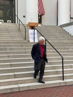 An old man walking down the steps of a building.
