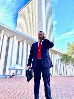 A man in a suit and tie talking on a cell phone in front of a building.
