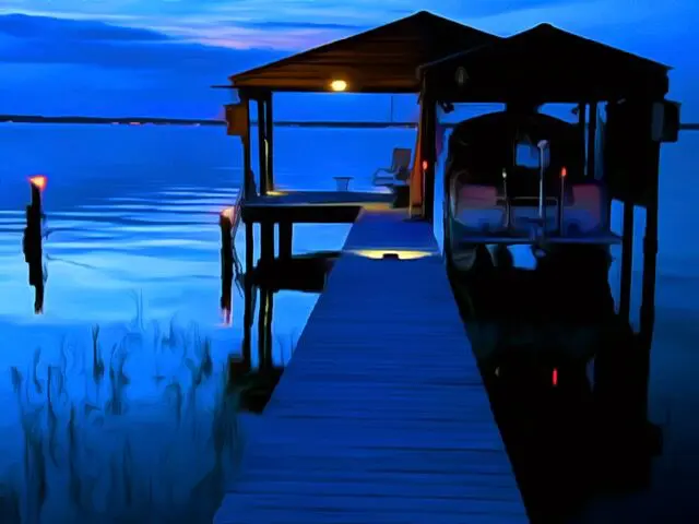 A dock with a boat on the water at dusk.